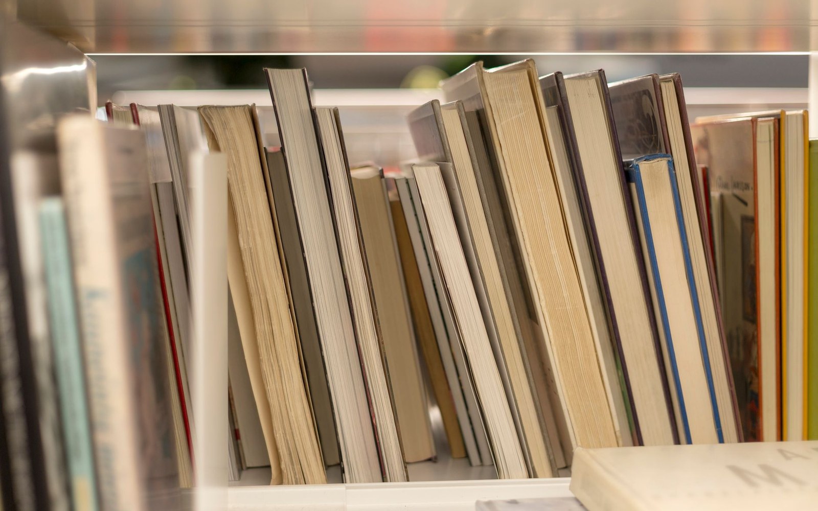 A tightly packed shelf of spines under a strip light