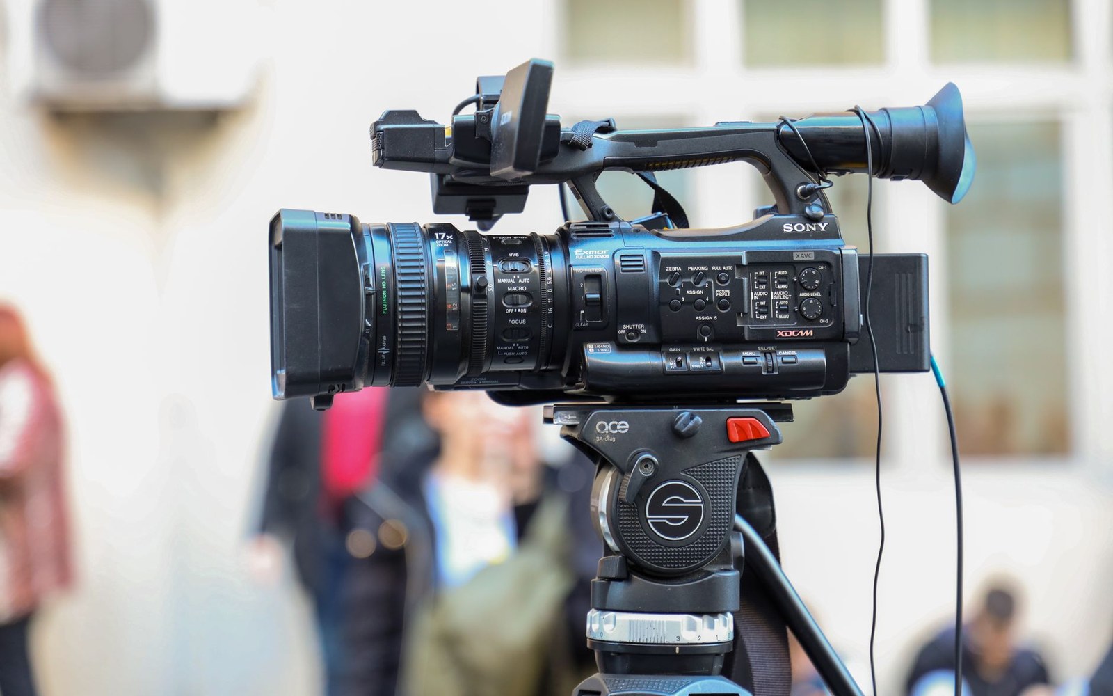 A Sony professional video camera mounted on a tripod outdoors