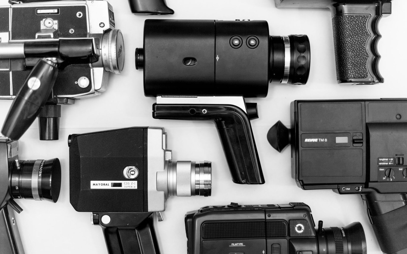 Vintage super 8 movie cameras arranged in rows on a flat surface
