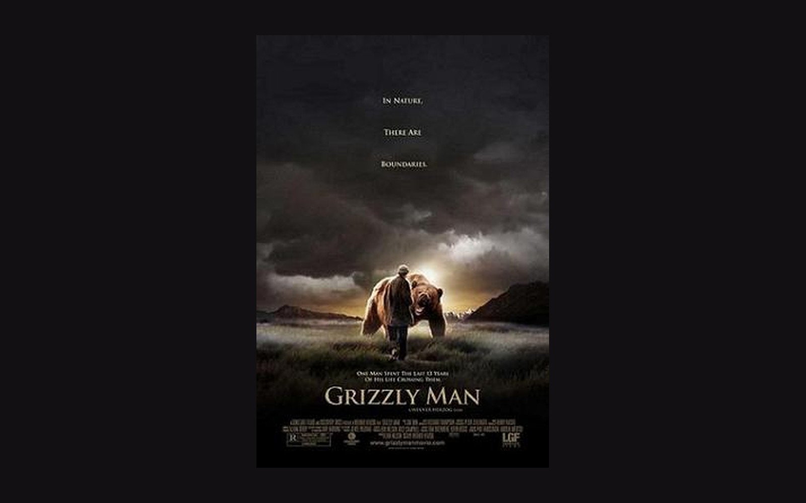 Movie poster for Grizzly Man showing a man walking beside a bear at sunset